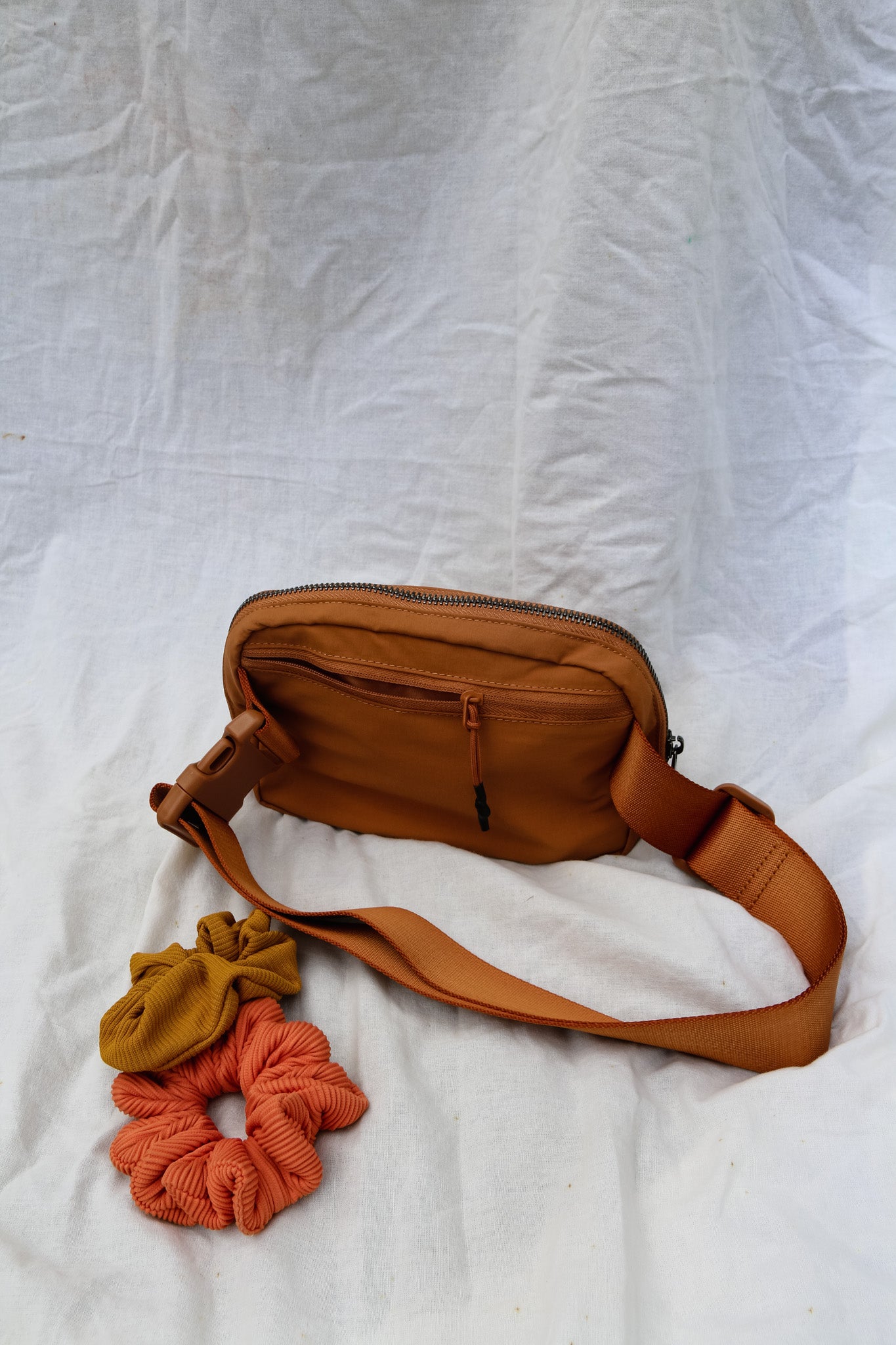A cross body bag made from recycled materials, resembling a 1L size and inspired by Lululemon. The bag features vibrant colors reminiscent of bikinis, making it a stylish and sustainable accessory from hawaii kailua oahu sustainable swimwear accessories tai swim co holo holo bag in terracotta