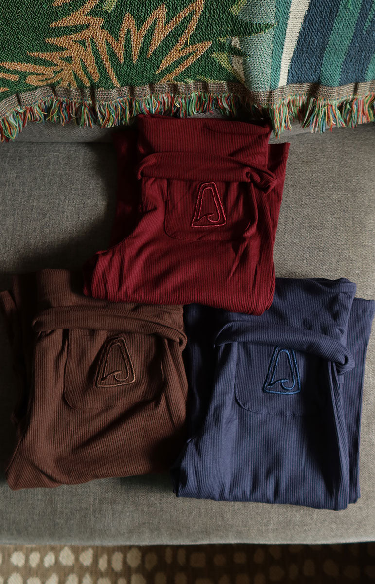 Folded shirts in red, brown, and blue on a textured surface