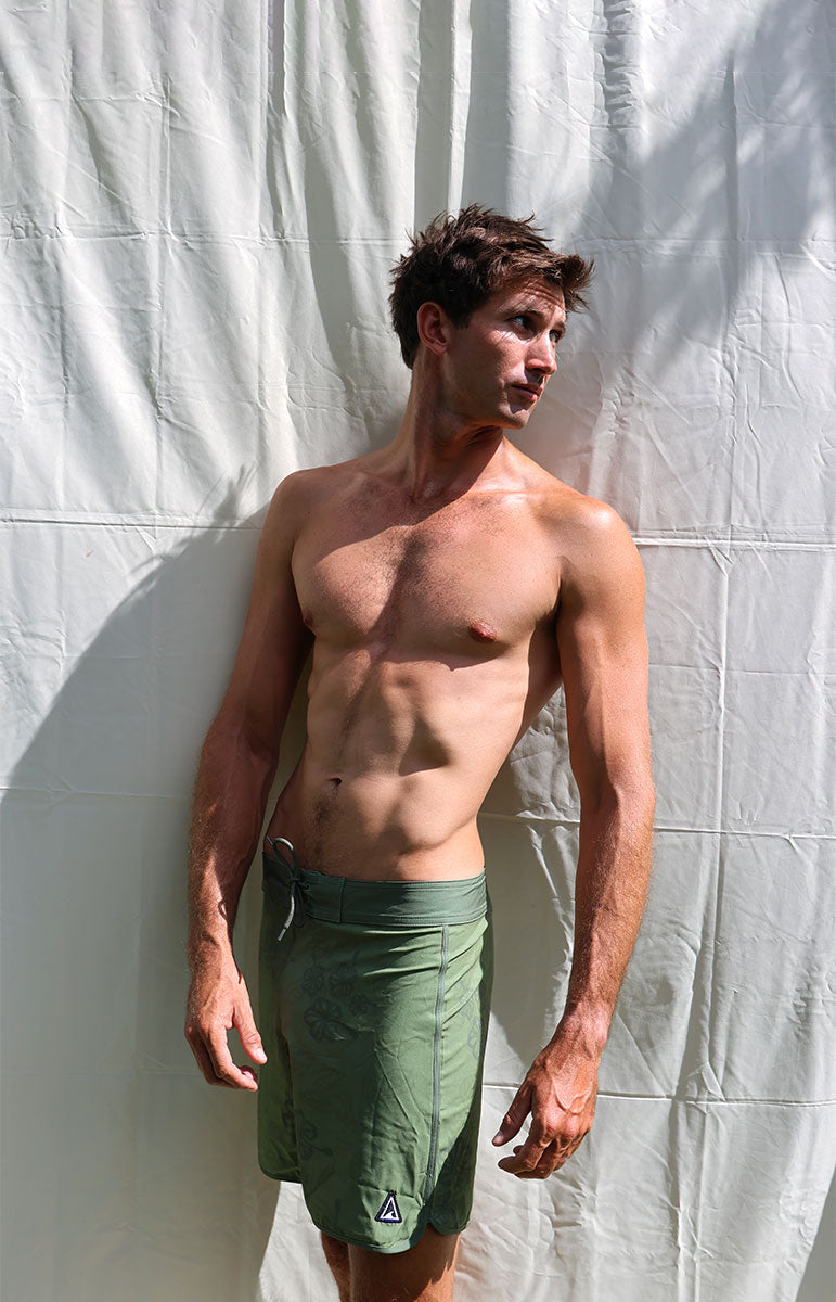 Austin boardshorts in Isthmus green hibiscus floral sustainable recycled swim trunks designed in hawaii oahu kailua 4 way stretch recycled repreve comfy shorts made from plastic water bottles 6 inch inseam with piping and back velcro pocket with patches and custom sewn on handmade logo patches with trees pinterest artsy photography background oahu hawaii photography background oahu kailua hawaii like vissla boardshorts hawaiian made local swimwear for men