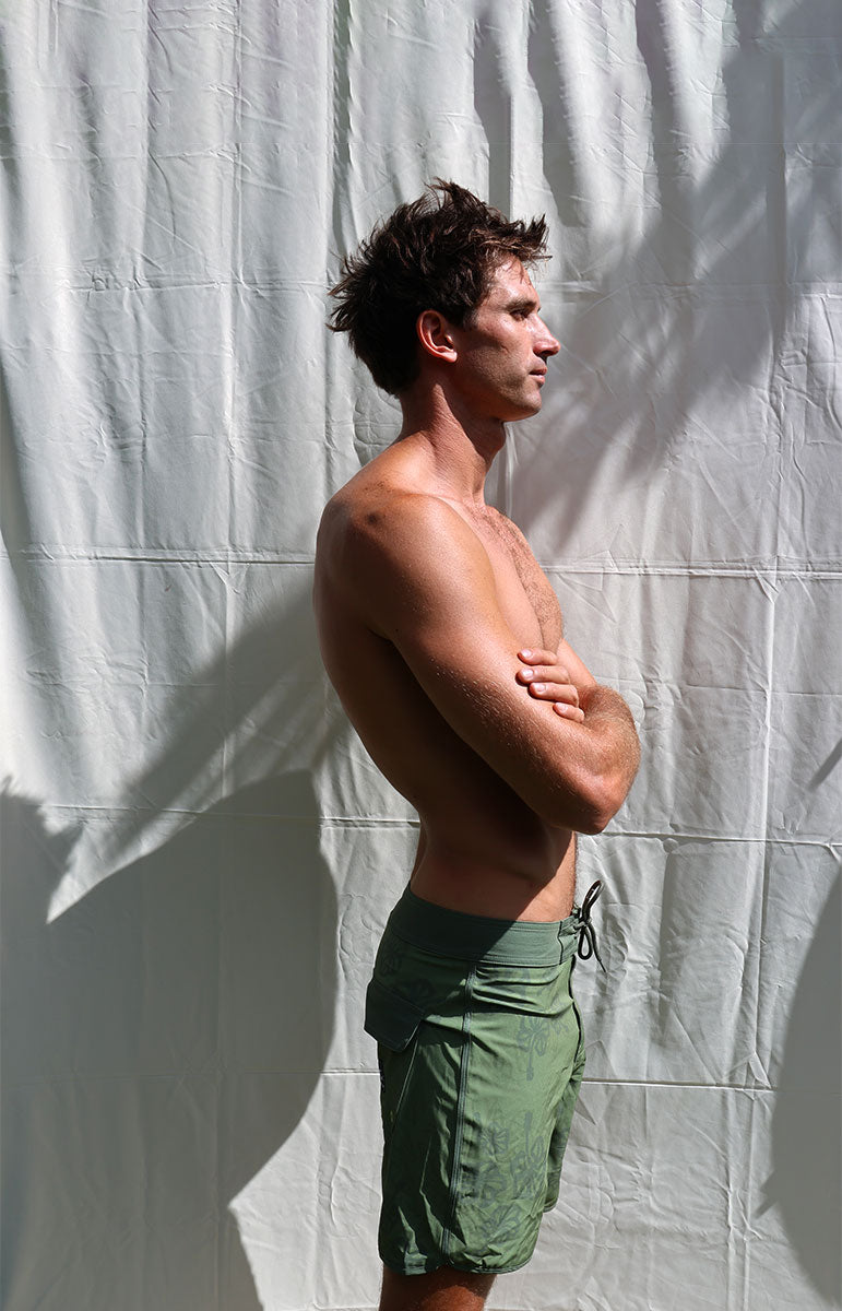 Austin boardshorts in Isthmus green hibiscus floral sustainable recycled swim trunks designed in hawaii oahu kailua 4 way stretch recycled repreve comfy shorts made from plastic water bottles 6 inch inseam with piping and back velcro pocket with patches and custom sewn on handmade logo patches with trees pinterest artsy photography background oahu hawaii photography background oahu kailua hawaii