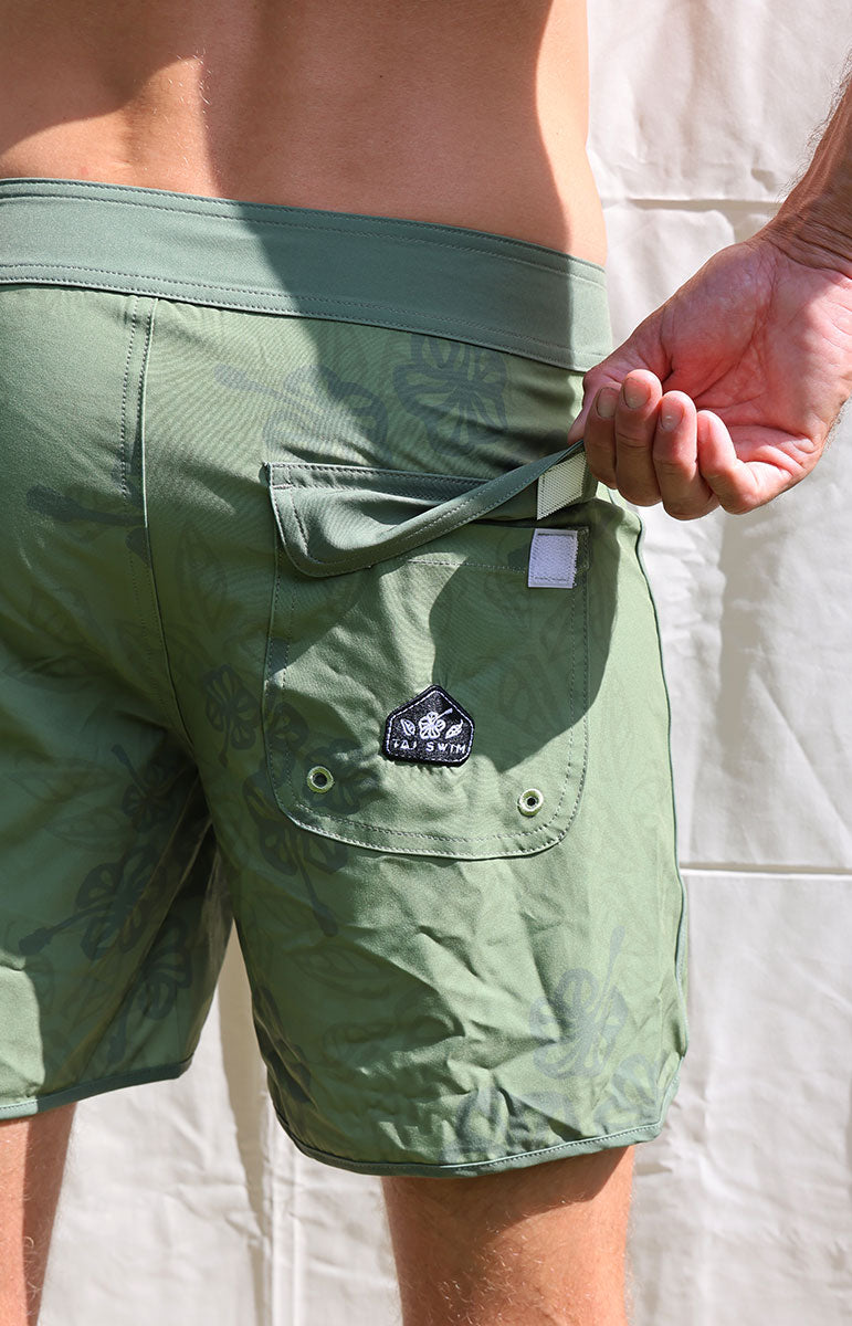 Austin boardshorts in Isthmus green hibiscus floral sustainable recycled swim trunks designed in hawaii oahu kailua 4 way stretch recycled repreve comfy shorts made from plastic water bottles 6 inch inseam with piping and back velcro pocket with patches and custom sewn on handmade logo patches with trees pinterest artsy photography background oahu hawaii photography background oahu kailua hawaii like vissla boardshorts