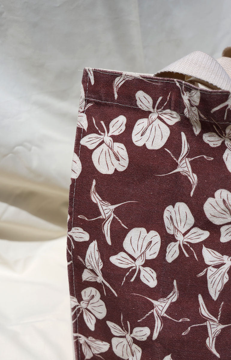 Close-up of a fabric with white floral pattern on a brown background on tai swim cotton tote bag