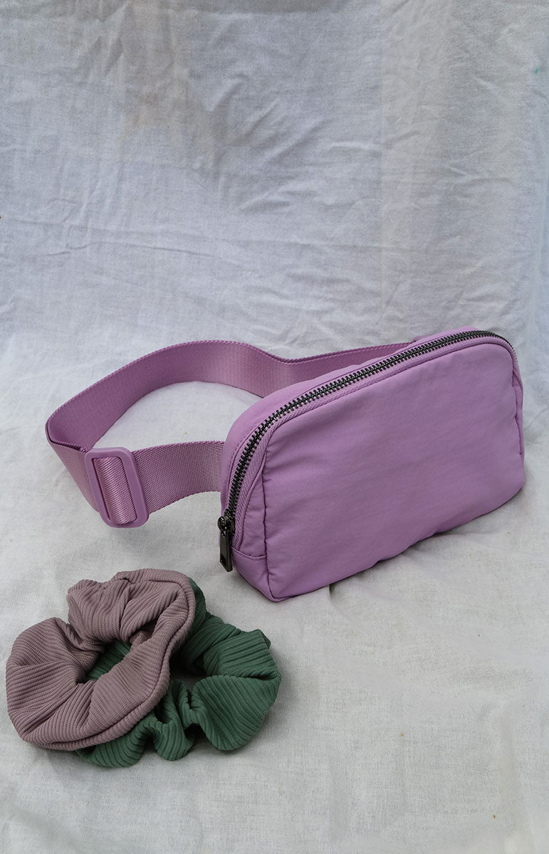A cross body bag made from recycled materials, resembling a 1L size and inspired by Lululemon. The bag features vibrant colors reminiscent of bikinis, making it a stylish and sustainable accessory from hawaii kailua oahu sustainable swimwear accessories tai swim co holo holo bag in ube