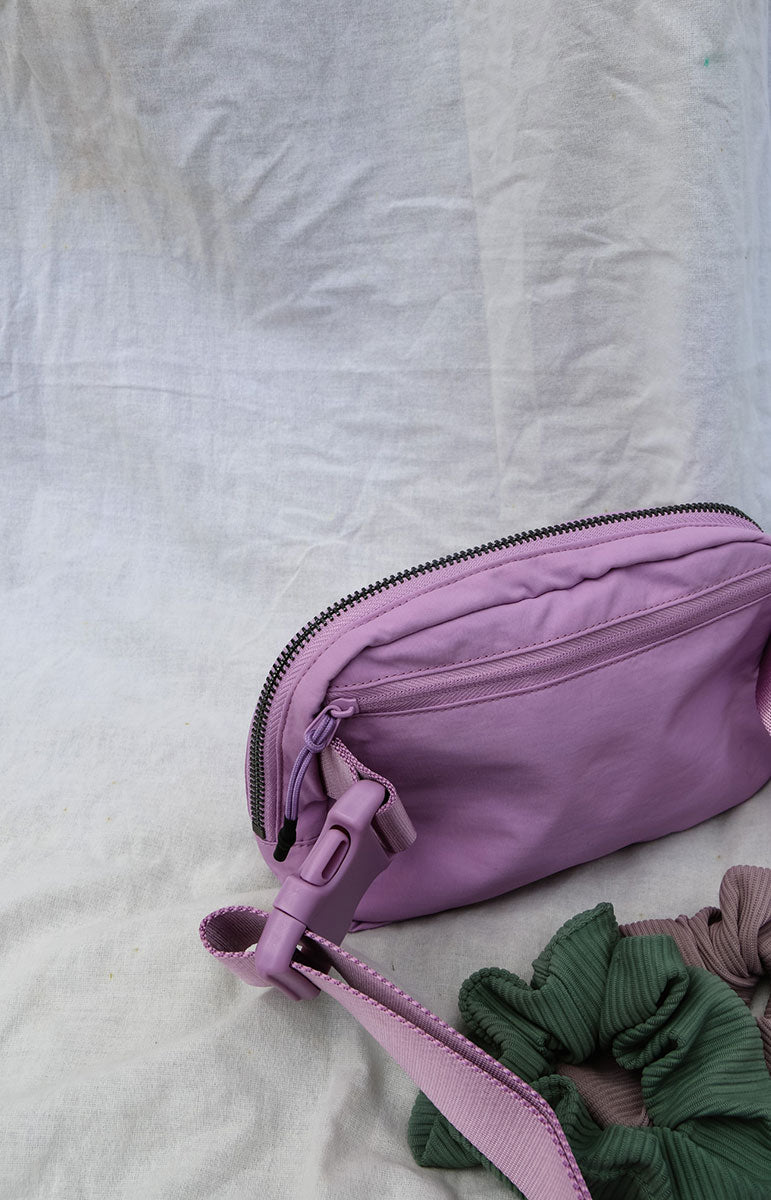 A cross body bag made from recycled materials, resembling a 1L size and inspired by Lululemon. The bag features vibrant colors reminiscent of bikinis, making it a stylish and sustainable accessory from hawaii kailua oahu sustainable swimwear accessories tai swim co holo holo bag in ube