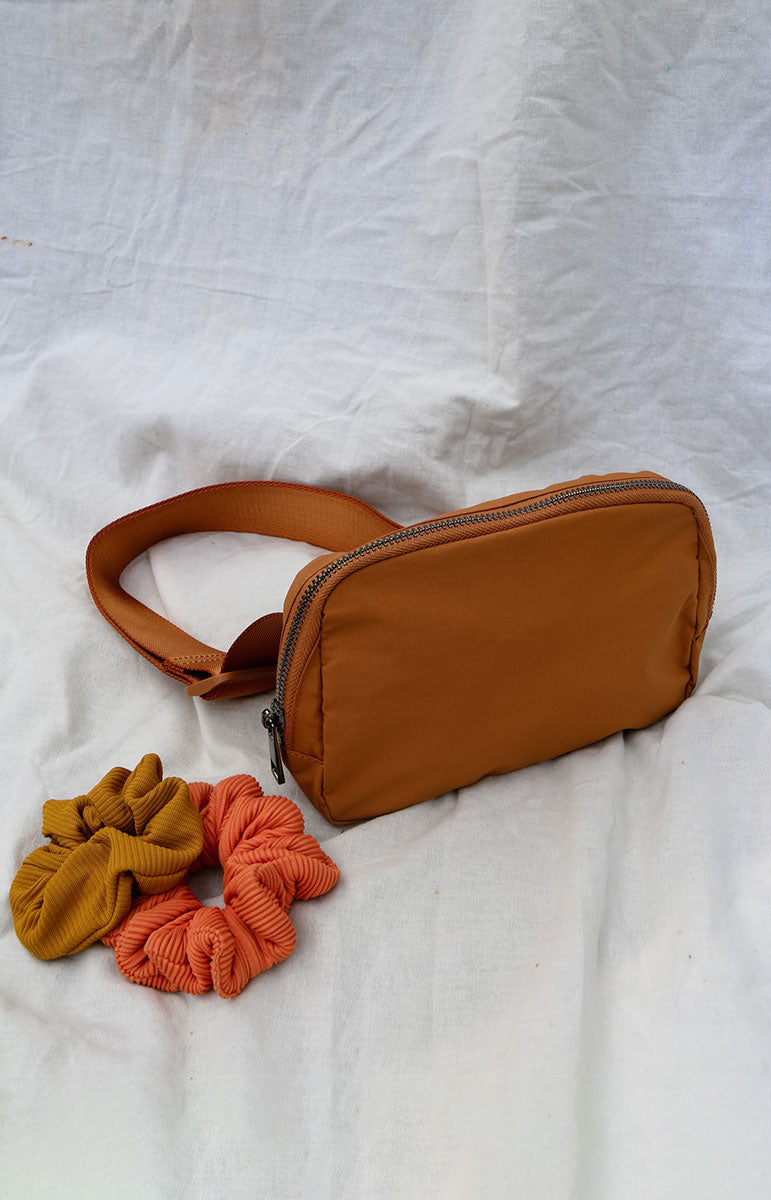 A cross body bag made from recycled materials, resembling a 1L size and inspired by Lululemon. The bag features vibrant colors reminiscent of bikinis, making it a stylish and sustainable accessory from hawaii kailua oahu sustainable swimwear accessories tai swim co holo holo bag in terracotta