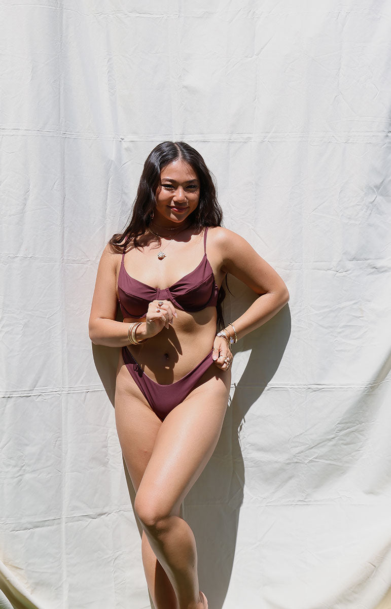 Woman wearing a burgundy bikini against a white backdrop swimwear bra top with underwire in rose hawaii cheeky skimpy tie back adjustable bikini from hawaiian islands