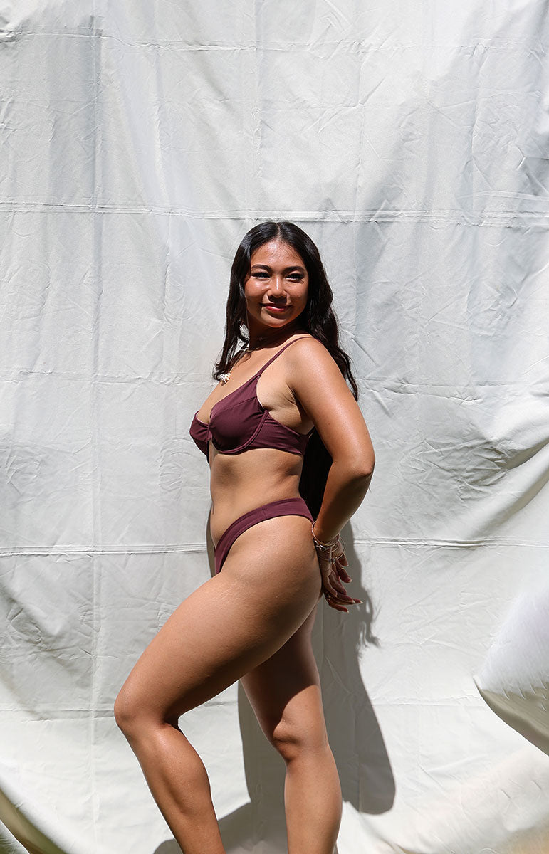 Woman wearing a burgundy bikini against a white backdrop swimwear bra top with underwire in rose hawaii cheeky skimpy tie back adjustable bikini from hawaiian islands
