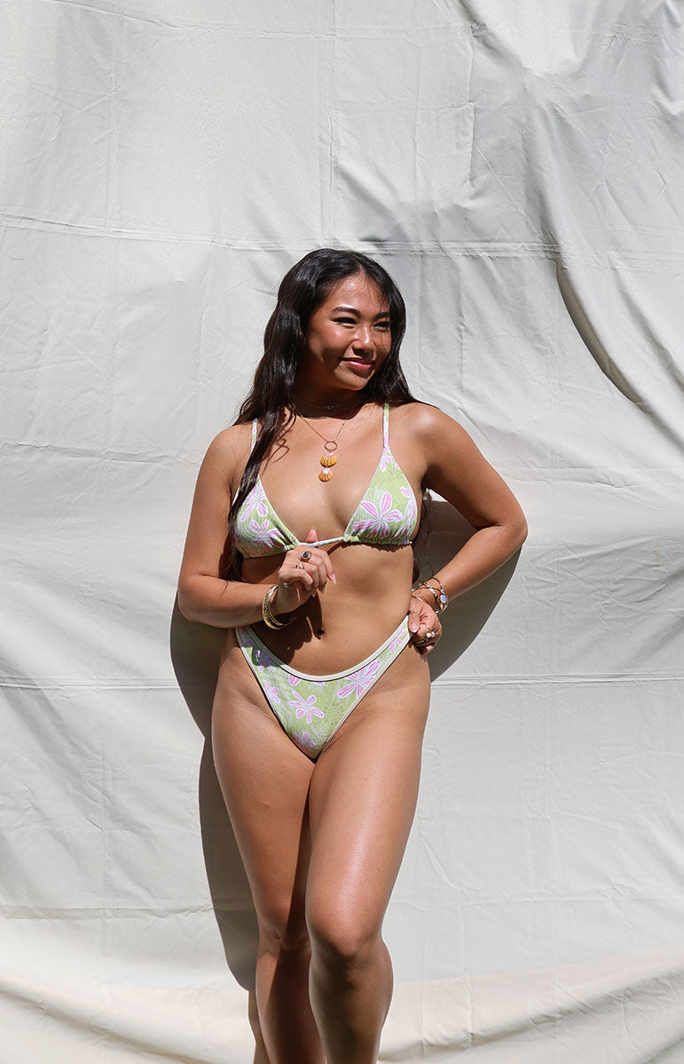 Woman wearing a floral bikini against a white background tai swim co joelle top in hawi green and pink floral hibiscus floral vintage hawaii print from kailua oahu hawaii