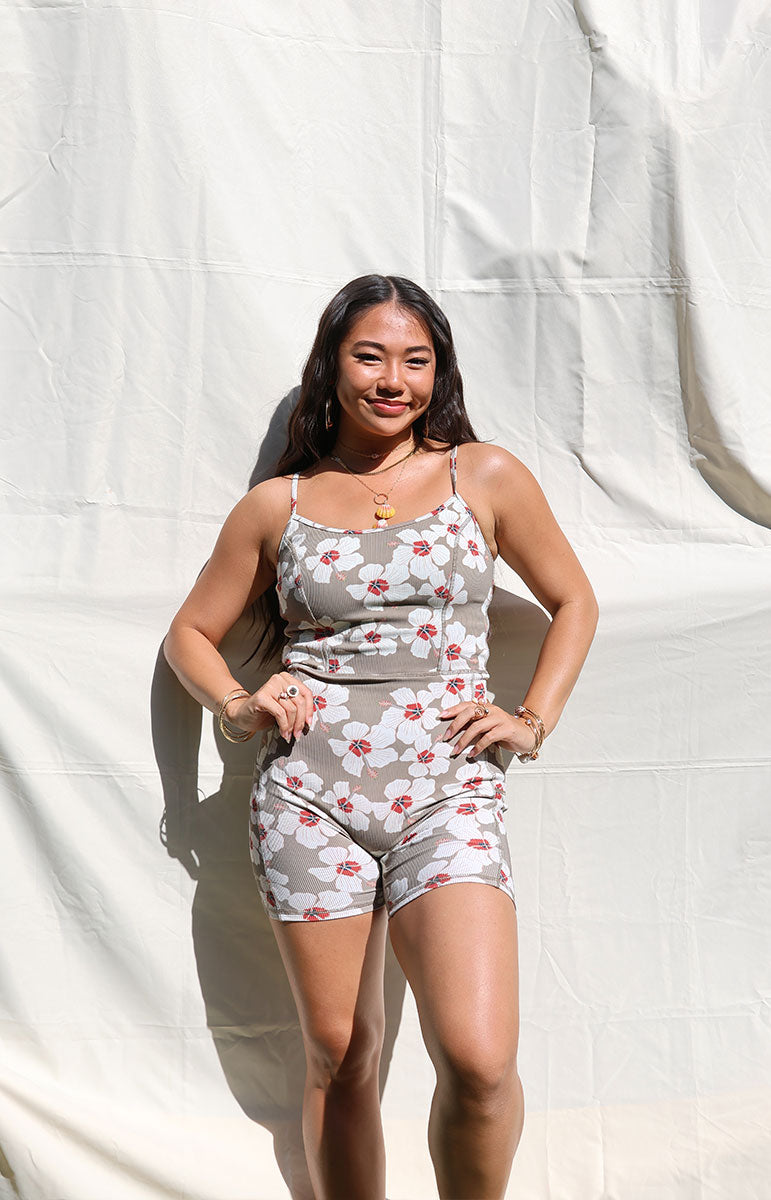 Woman wearing Tai Swim Co's fitted Kimi Romper in ribbed brown Kailua print with white hibiscus flowers, seamless design, photographed from the back in natural light summer 2025 handmade bikini and accessories from the hawaiian islands