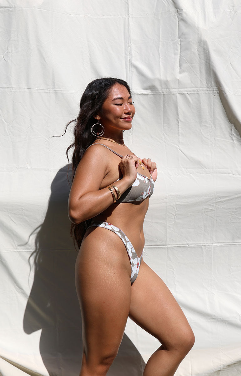 tai swim co mariah thong bottom in kailua white floral hibiscus hawaiian bikini print swimwear pattern from windward side oahu bikini top and bottom in matching high waisted set sustainable cheeky bikinis on bright sunny photography day in kailua hawaii
