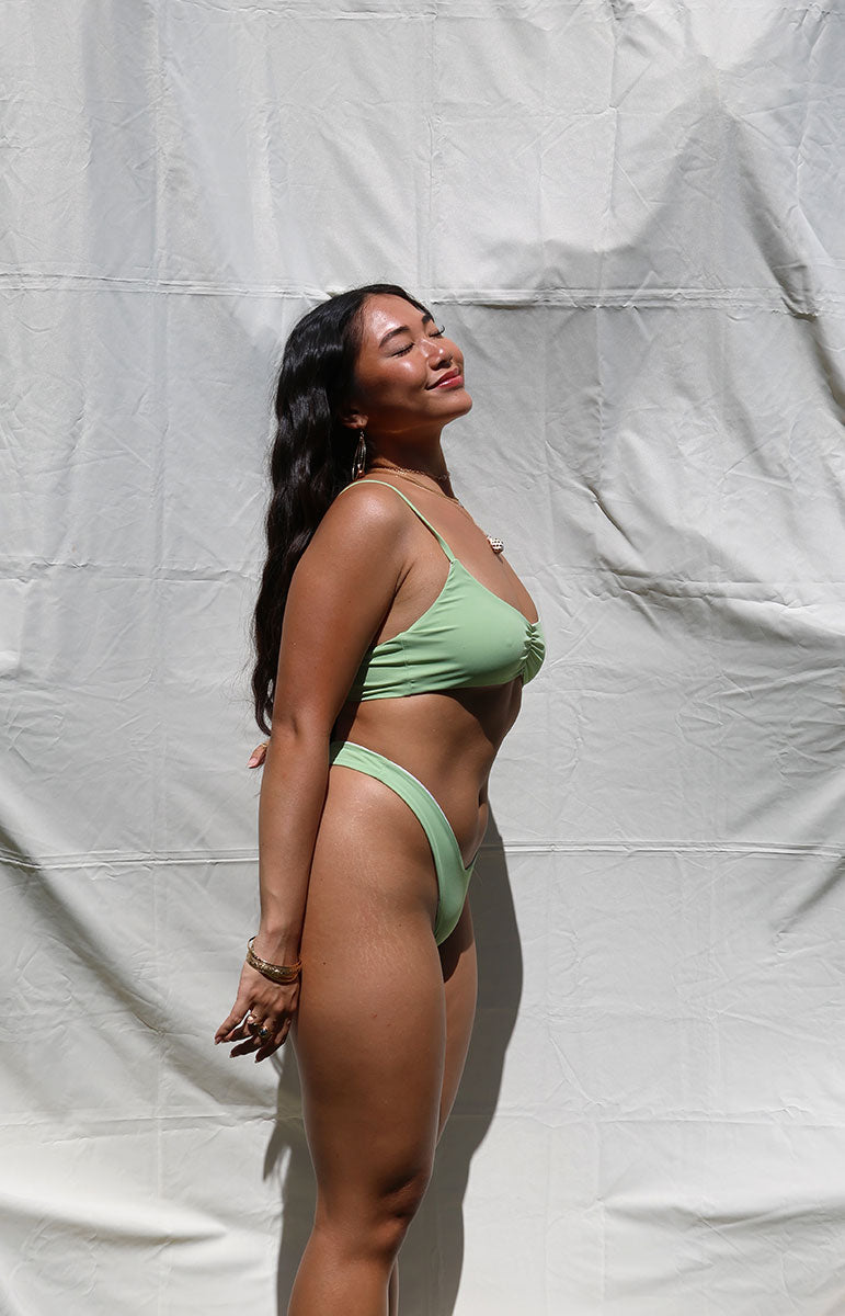 tai swim co mariah bottom in matcha green sunny day in seamless reversible sustainable bikinis from tai swim co cheeky designer swimsuits made to mix and match in bright sunlight photography island day basic classic bikini bottoms