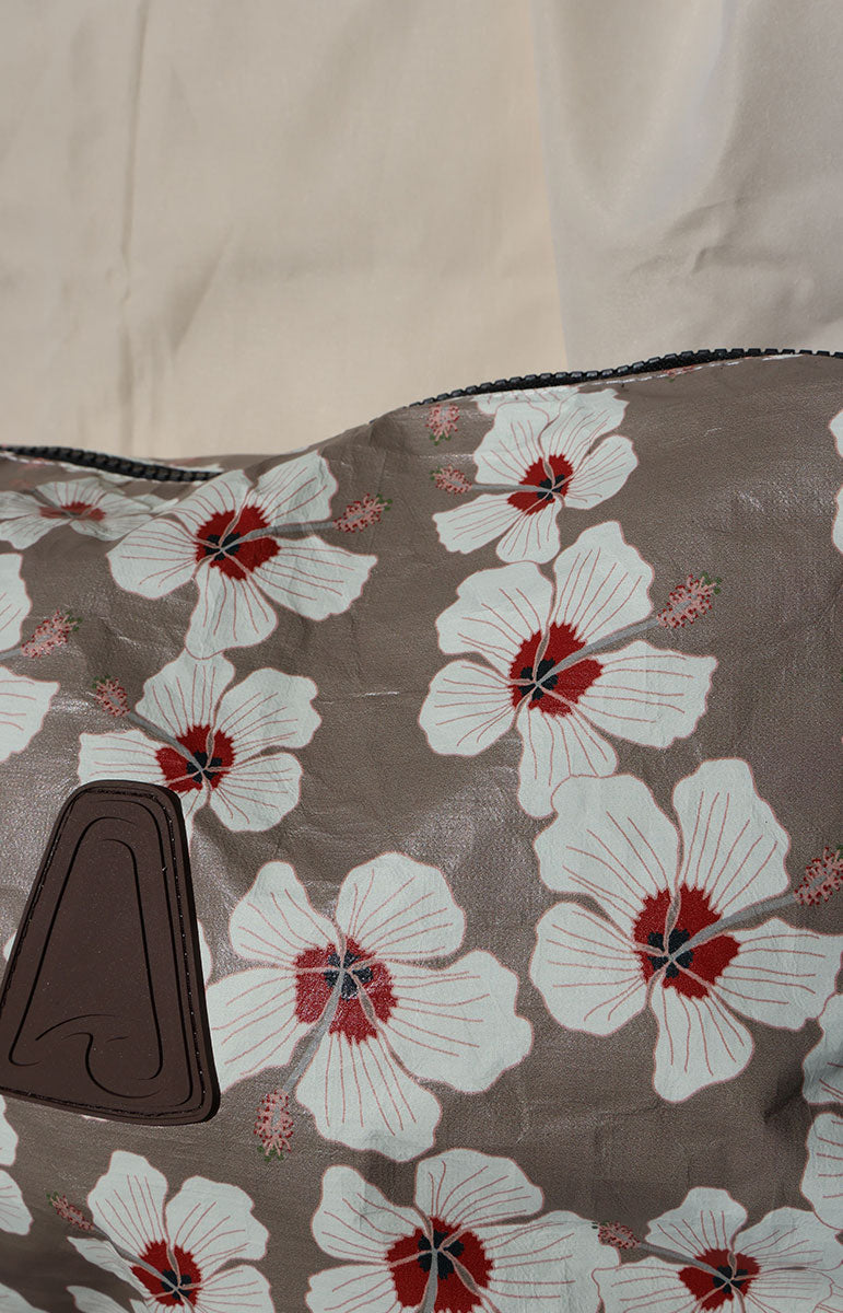 Floral-patterned tai swim kailua fabric with white flowers and red centers on a brown background