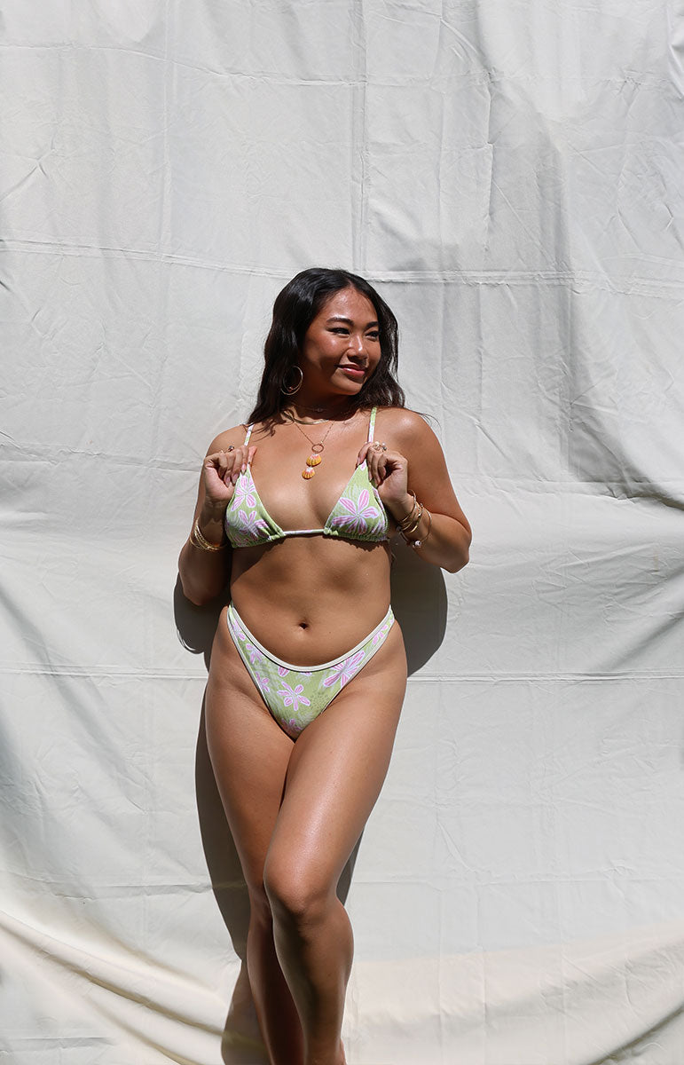 Person wearing a bikini against a plain background tai swim co quinn bottom in hawi green piping floral hawaii cheeky bikini from oahu hawaii with joelle top from tai swim co