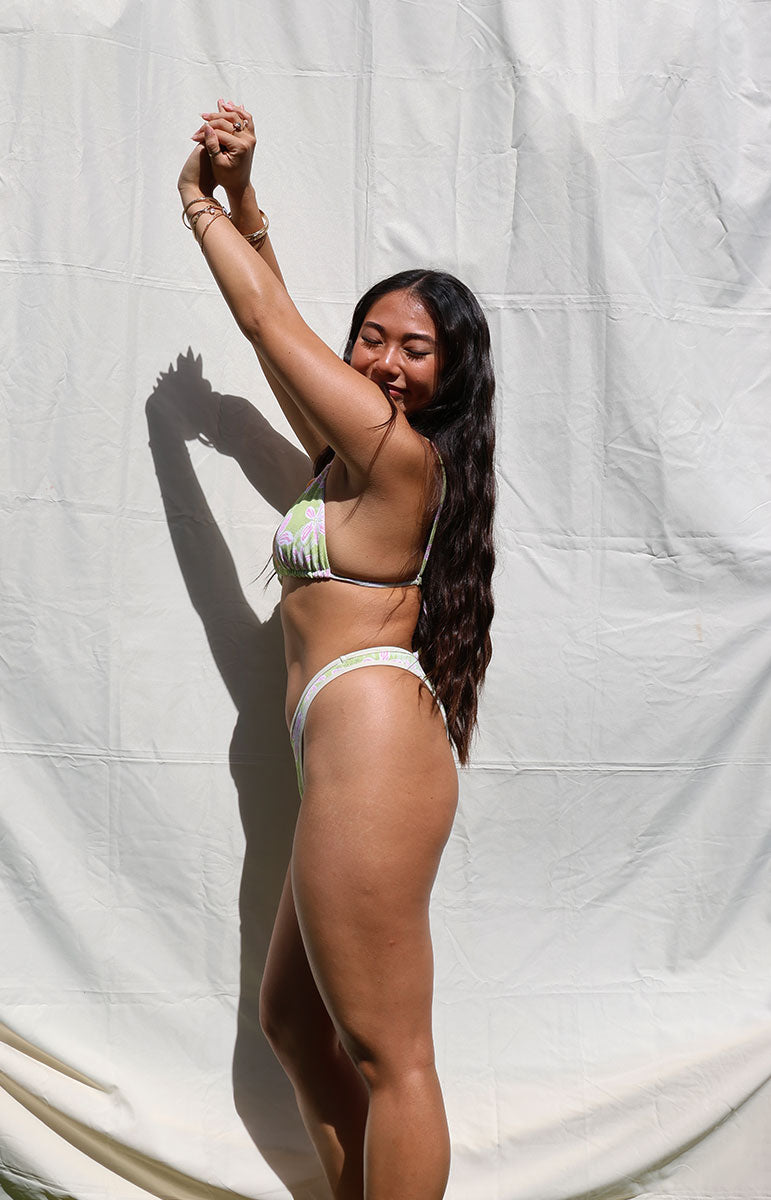 Person wearing a bikini against a plain background tai swim co quinn bottom in hawi green piping floral hawaii cheeky bikini from oahu hawaii with joelle top from tai swim co