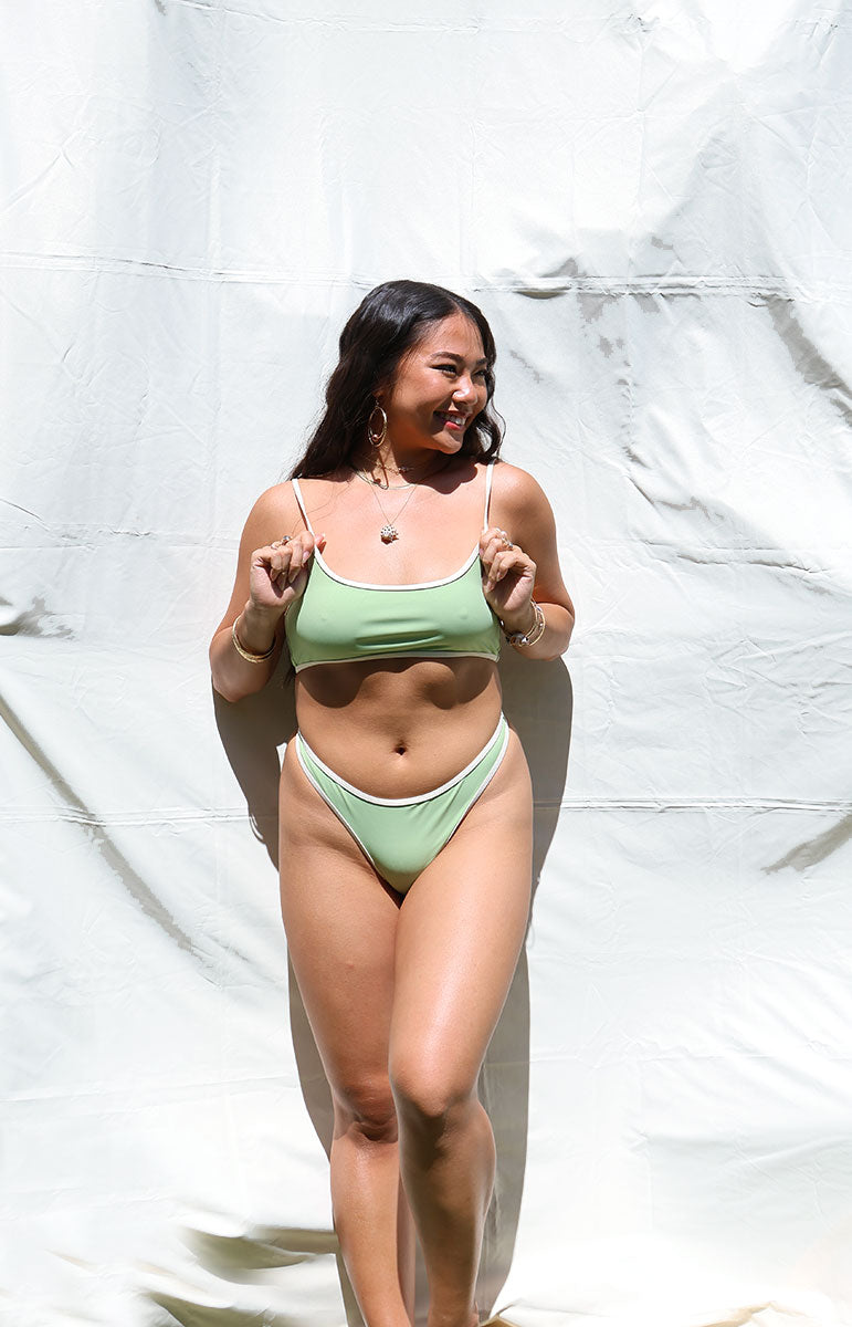 tai swim co quinn bottom in matcha green ribbed bikini from hawai'i skimpy cheeky swimsuits made with eco friendly green textured ribbed fabric with lines in green and white pattern swimwear in the hot bright lighting natural sun outside lighting in hawaii