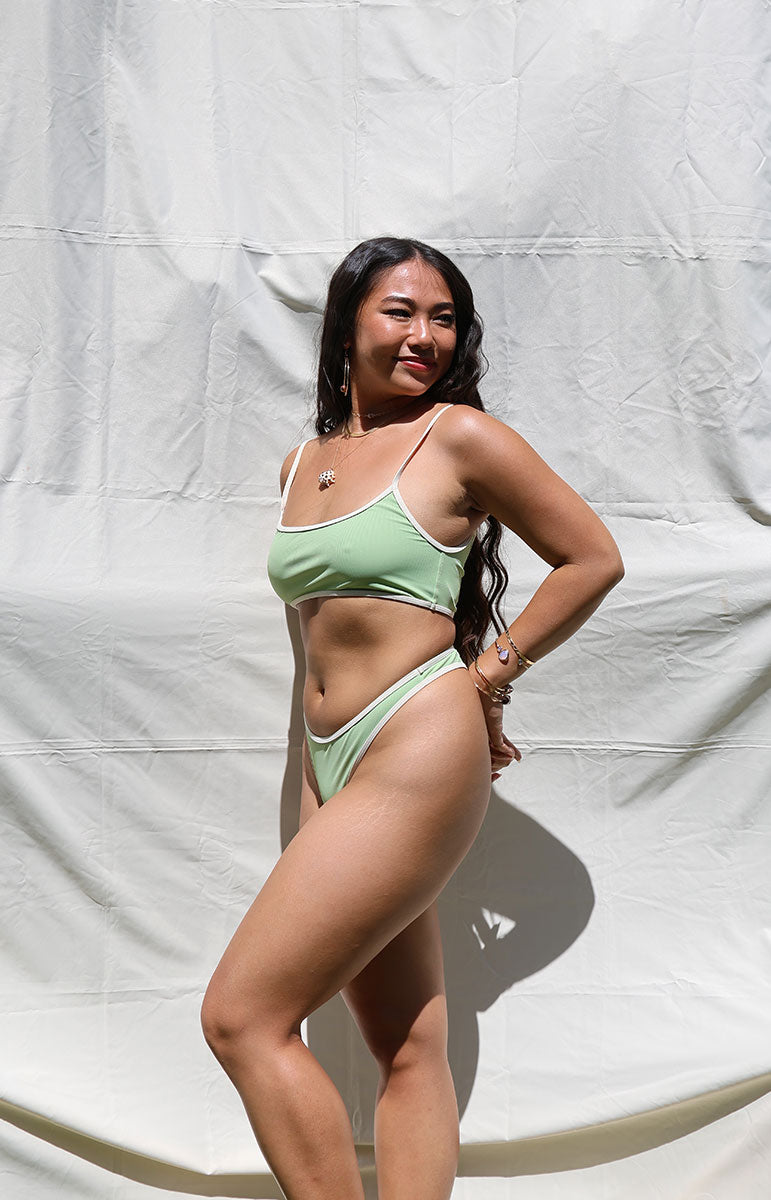 tai swim co matcha quinn top and bottom in a scoop neck tank top with ribbed textured fabrics in bright sun lighting in hawaii from kailua oahu hawaii sustainable bikinis and eco friendly swimwear bright sage pastel earthy green