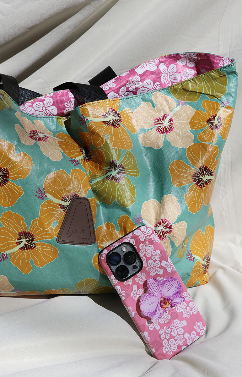 milo and hana tai swim co Floral-patterned reversible tyvek bag with a phone case on a white surface