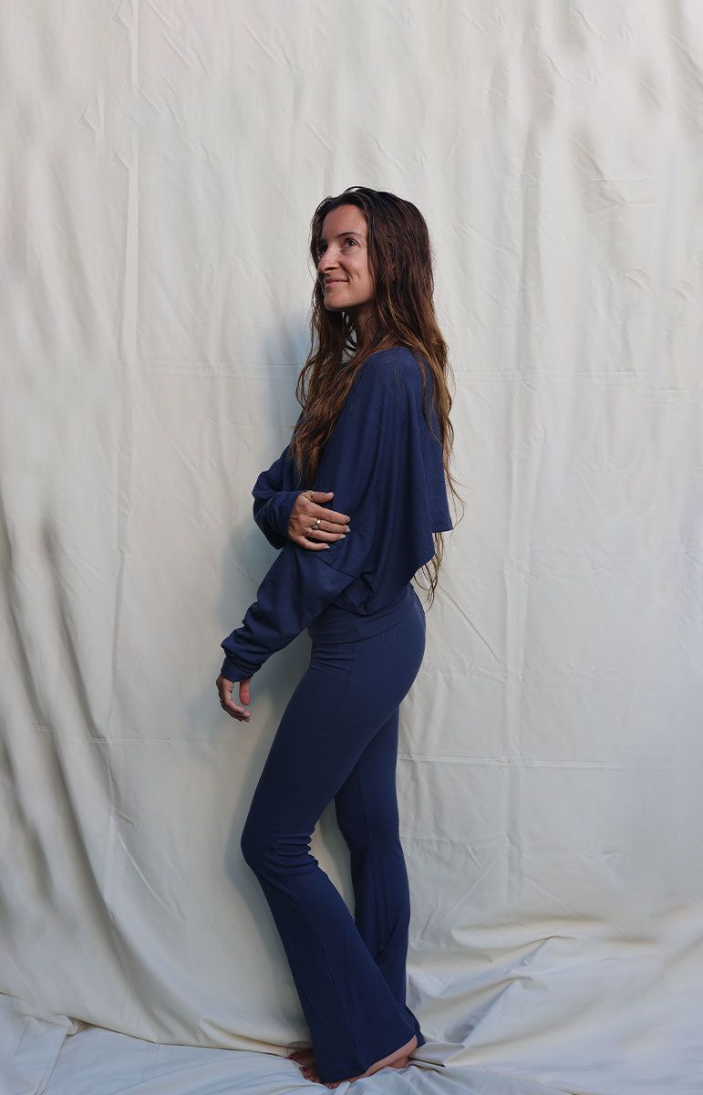 Person wearing a blue outfit standing against a plain white background tai swim co blue navy rift cotton lounge foldover low rise flare pant from hawaii