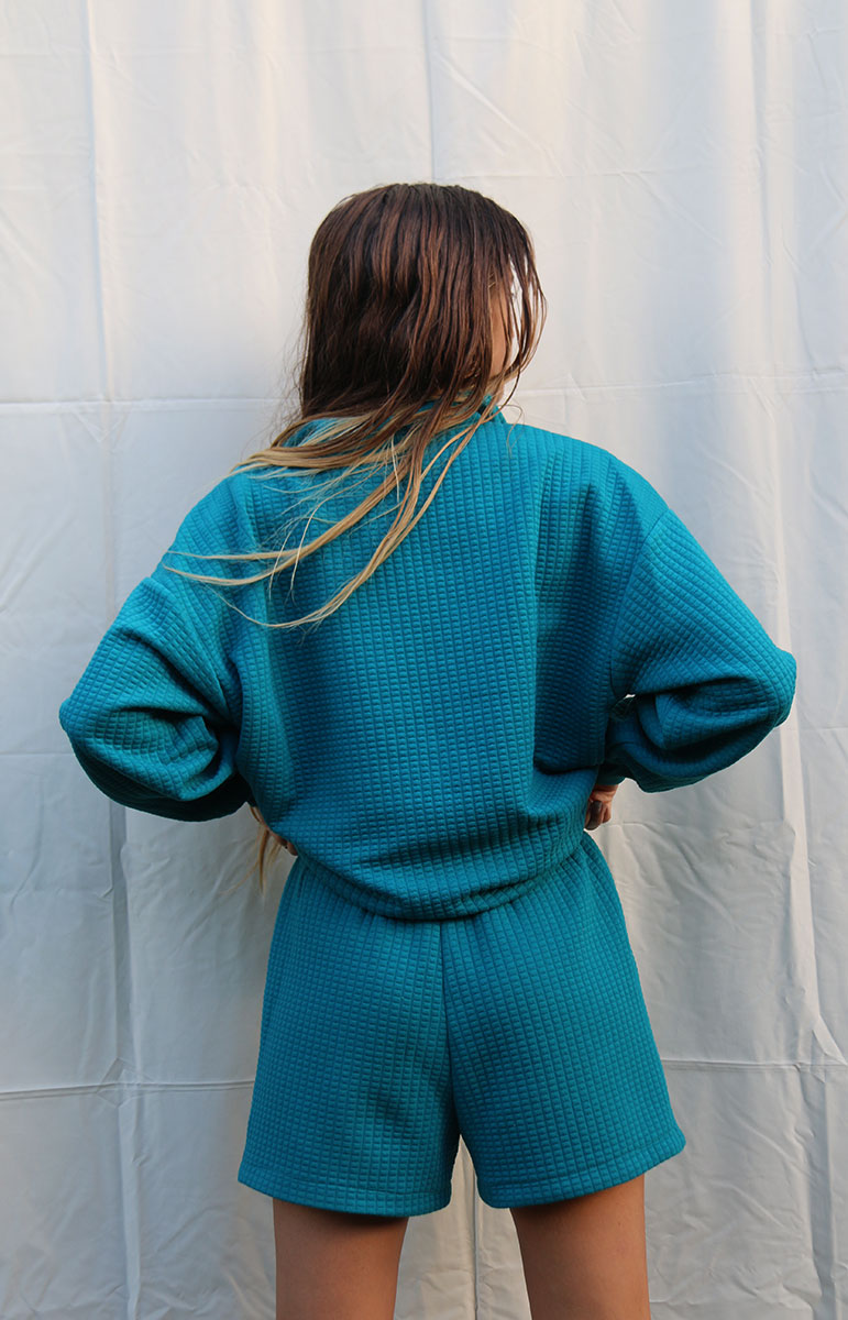 Elevate Your Summer Comfort with the Shannah Matching Shorts by Tai Swim Co. These cozy bottoms feature a textured design and elastic waistband for a perfect fit. Crafted from a recycled waffle cotton/poly blend, they combine sustainability with style. Available in classic swim colors with a custom Tai Swim logo, these shorts offer a relaxed yet chic look. The soothing blue shade and tan embroidery add a touch of elegance to your casual attire