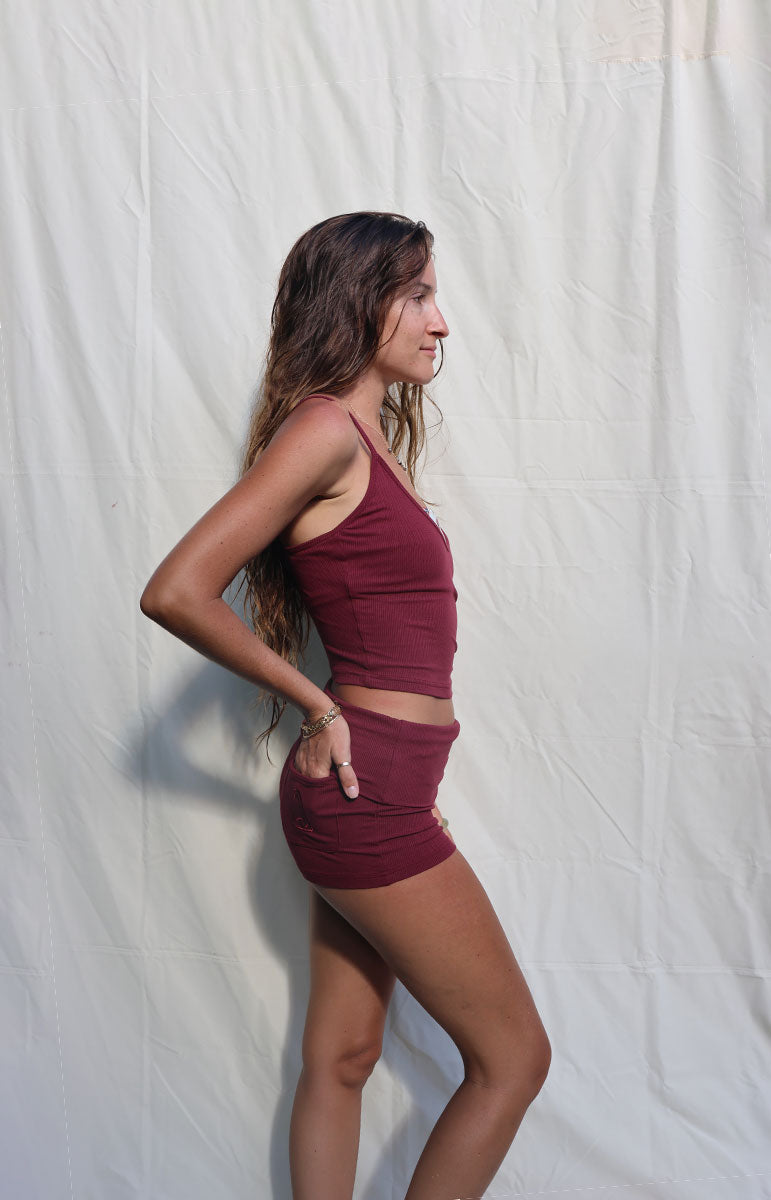 Woman wearing a maroon athletic outfit against a white background tai swim co hawaii rose shannah tank top and shannah shorts made from organic cotton ribbed comfy lounge set