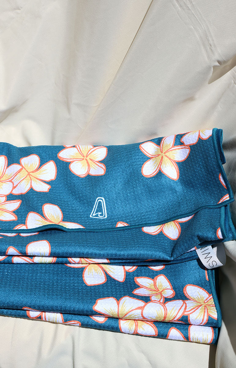 tai swim co shop keiko collaboration towels with blue and pink plumeria tropical hawaii flowers from oahu kailua hawai'i with holding hanging loop for convenience