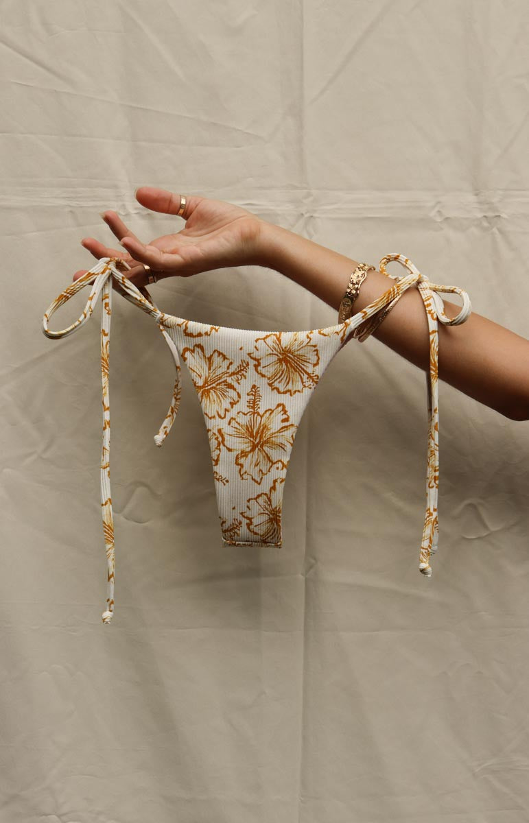 tai swim co woman wearing lauryn top and bottom in waimea yellow floral hibiscus print from eco friendly hawaiian swimwear brand tai swim from kailua oahu hawaii