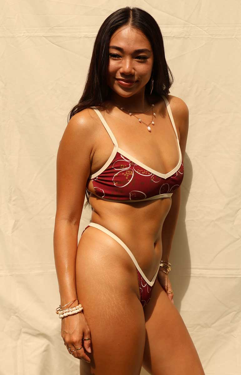 Woman wearing a red and white bikini against a beige background tai swim tyler top cowry swimwear