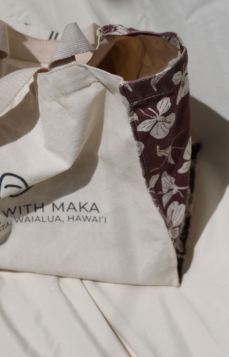 Canvas bag with floral lining and 'YOGA WITH MAKA' branding on a white surface