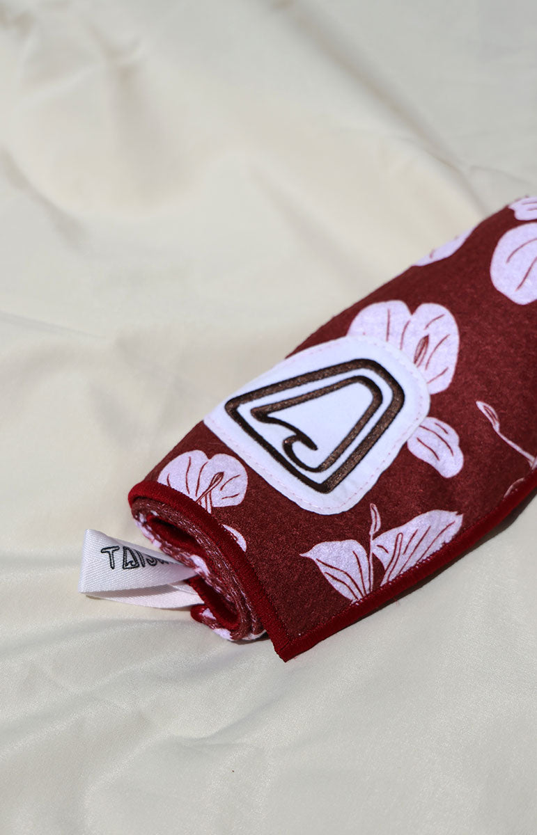 Red fabric with white floral pattern and a visible tai swim co brand label on a beige background