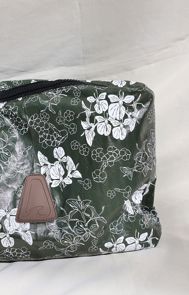 dark green puakenikeni and ginger tai swim co tyvek floral-patterned pouch with a brown patch on a white background