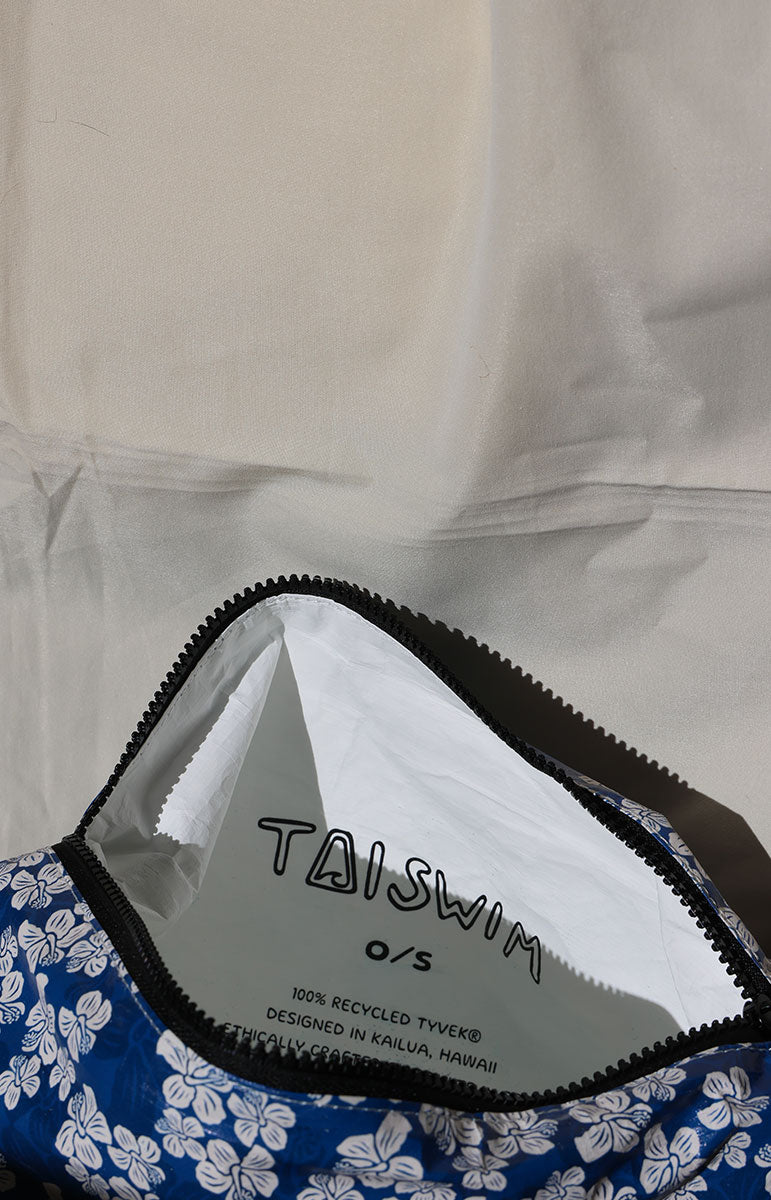 Close-up of a blue and white floral patterned garment with 'TAISWIM' label on a beige background