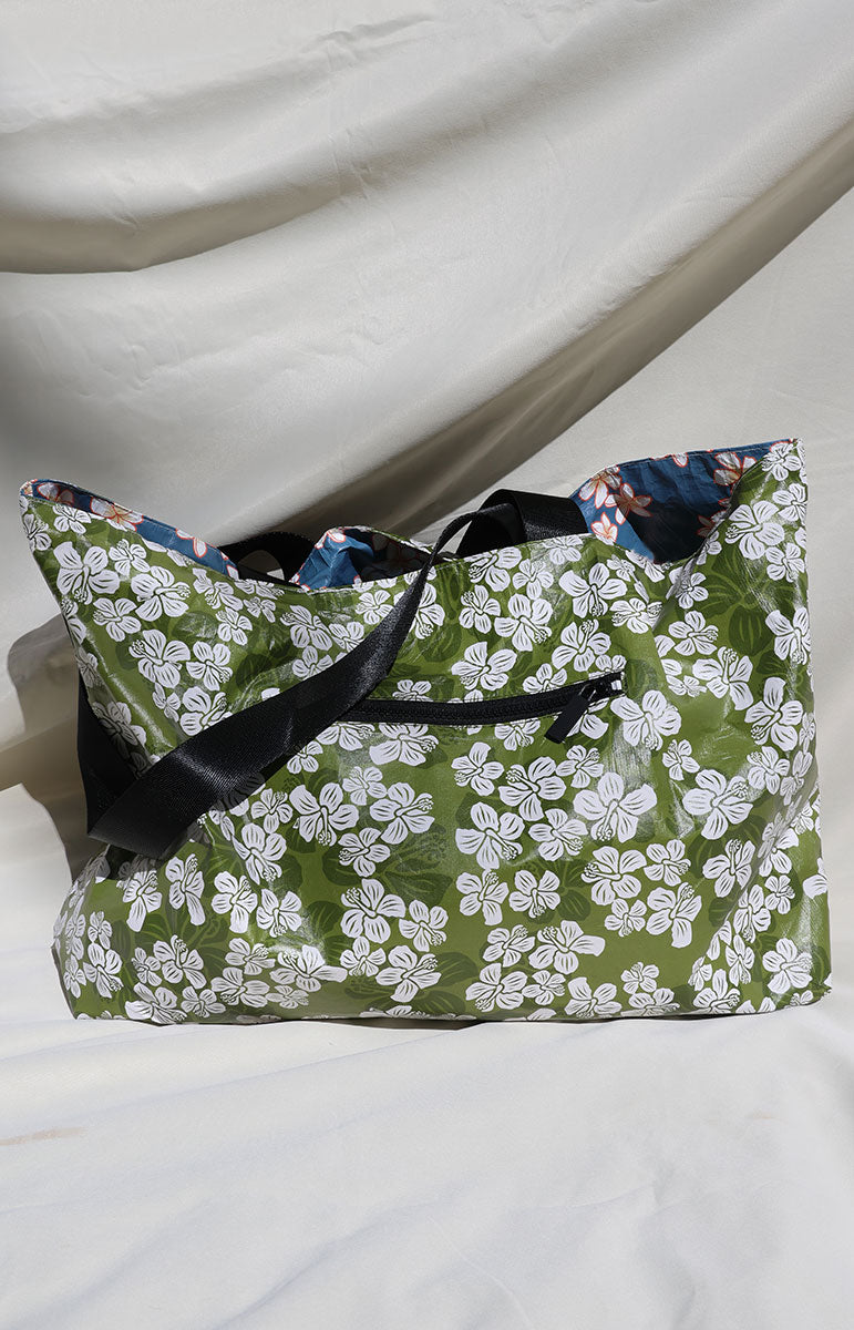 Green floral-patterned floral waialua white hibiscus reversible bag with black straps and zippers with blue plumeria tyvek recycled bag from tai swim co oahu hawaii