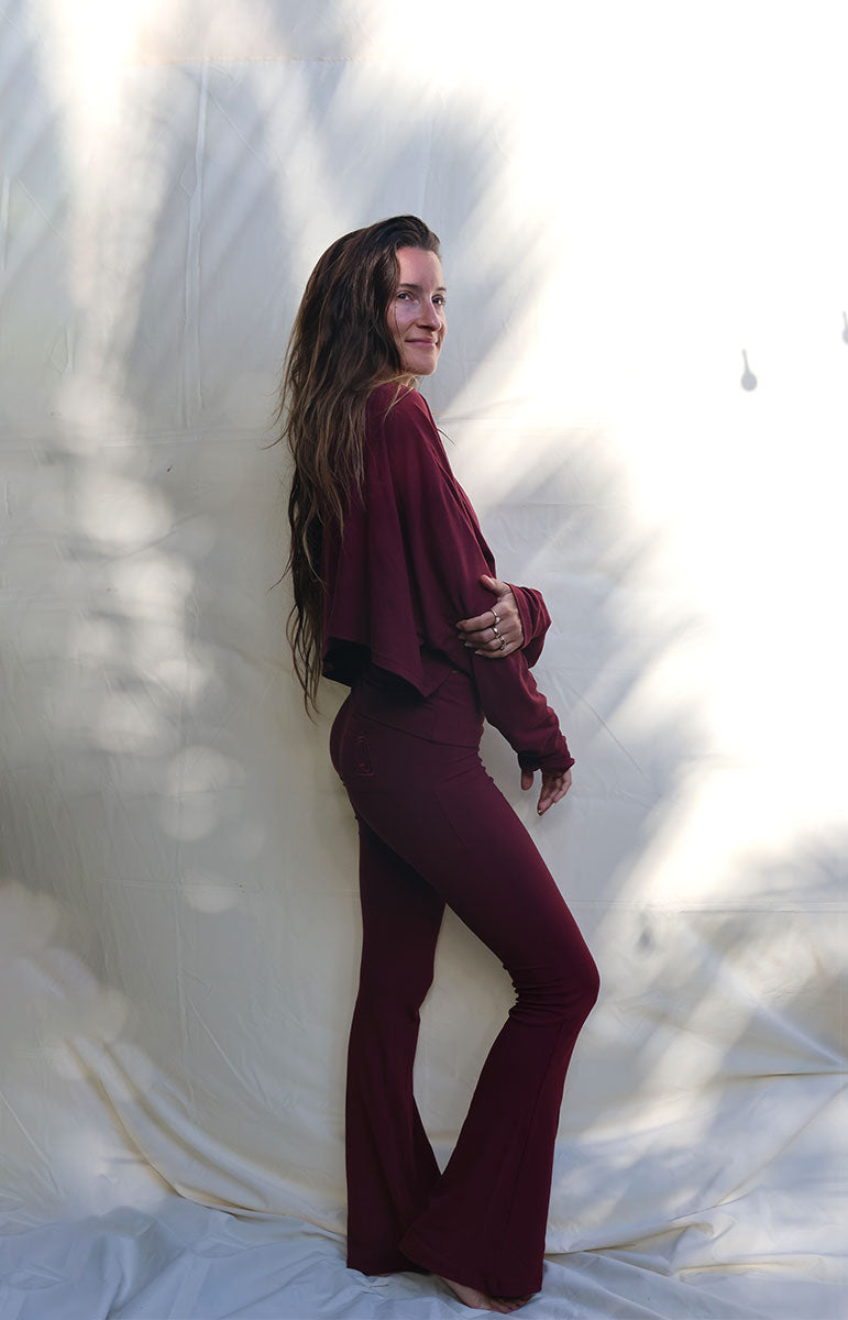 Woman wearing a burgundy outfit standing against a white curtain tai swim co shaiann set in rose comfy cotton lounge ribbed eco friendly cozy sets
