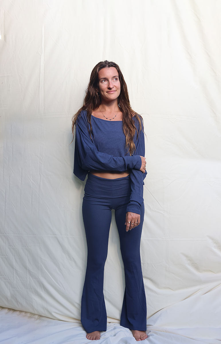 Woman wearing a blue outfit standing against a white background tai swim co shaiann top in rift long sleeve ribbed cotton crop top