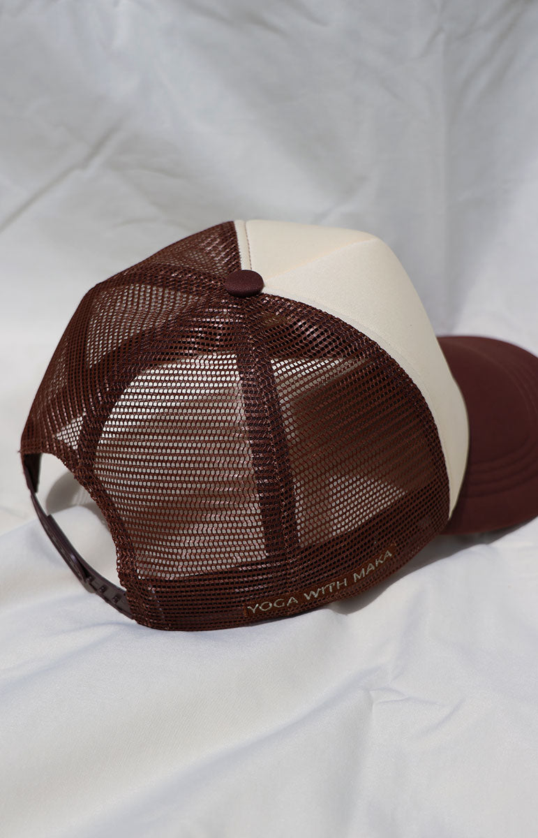 Maroon and beige cap with a tai swim logo in green ginger print on a white background brown yoga with maka collaboration event north shore oahu hawaii