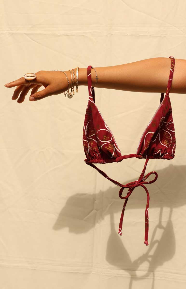 Woman wearing a tai swim cowry joelle top red bikini with a cowry shell hawaiian pattern against a beige background